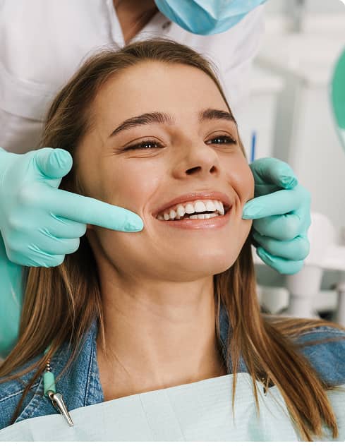Warragul Smiles Dental | Dental patient smiling as a dentist gently checks her teeth during an exam